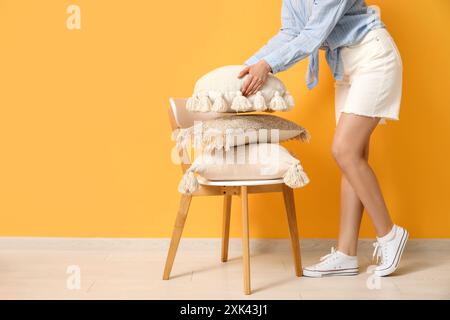 Woman putting pillow on chair in room Stock Photo