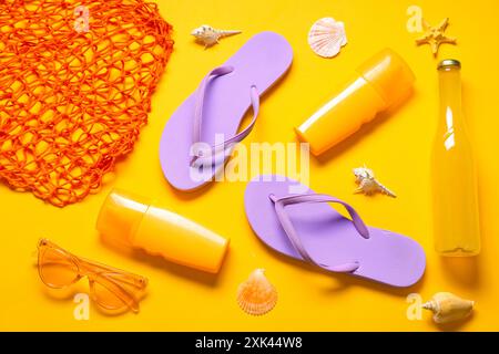 Flip-flops, bottle of juice and beach accessories on orange background Stock Photo