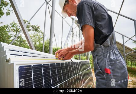 Worker measuring metal beams with measuring tape for installing solar panels. Cropped image of man in workwear Stock Photo