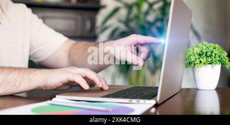 Man working on laptop at home office. Close-up of male hands typing on laptop keyboard, investment trading Stock Photo