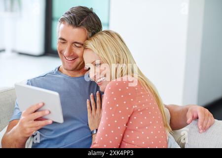 Mature, couple and happy on tablet on couch, relaxing and smile for social media in home. Streaming video, digital platform and website on movie Stock Photo