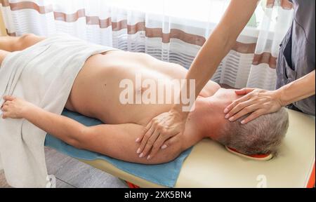 Female manual therapist performing physical therapy on mid aged male patient. Stock Photo