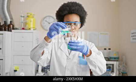 African woman scientist conducting experiment in laboratory wearing lab coat and safety glasses Stock Photo