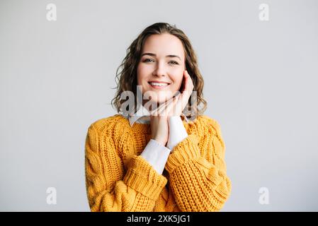 Smiling Curly-Haired Woman Looking at Camera. A joyful young woman with curly hair, smiling and looking directly at the camera. Ideal for advertising Stock Photo