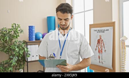 A handsome young hispanic man with a beard, working in a rehab clinic, attentively reviews medical documents. Stock Photo