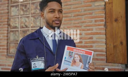 African-american man in uniform showing a missing person flyer outdoors in a city street. Stock Photo