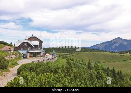 A summer morning view of the Otto Schutzhaus on the Rax, with the majestic Schneeberg in the background under a cloudy sky. The scene captures the idy Stock Photo