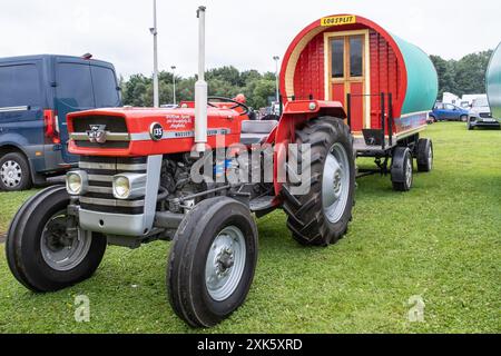 Ballymena, Northern Ireland - July 20th, 2024: vintage tractor and steam engine rally, red classic Massey Ferguson with retro style caravan on trailer Stock Photo