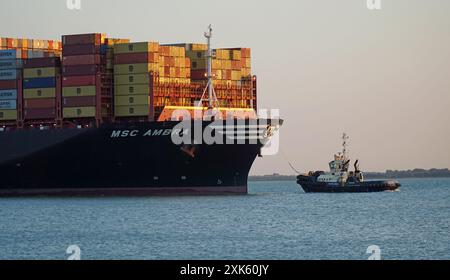 Container Ship being pulled into Felixstowe Port by Tug in early evening. Stock Photo