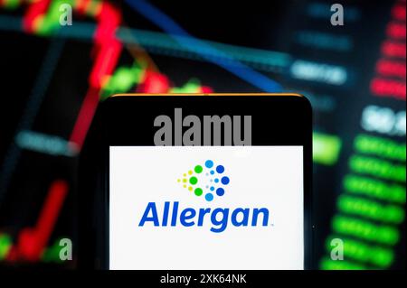 In this photo illustration, the Irish-domiciled pharmaceutical company, Allergan, logo seen displayed on a smartphone with an economic stock exchange index graph in the background. Stock Photo