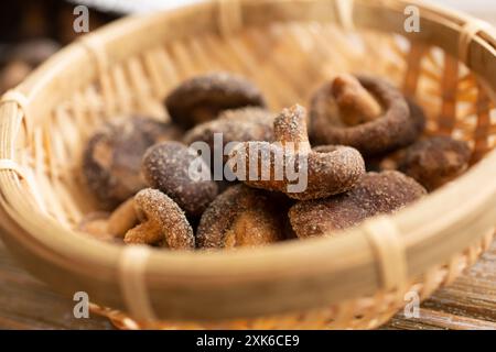 A closeup view of a pile of dried shiitake mushroom chips inside a bamboo basket. Stock Photo