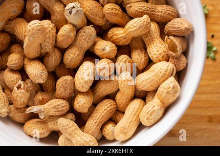A top down view of a bowl of peanuts in their shells. Stock Photo