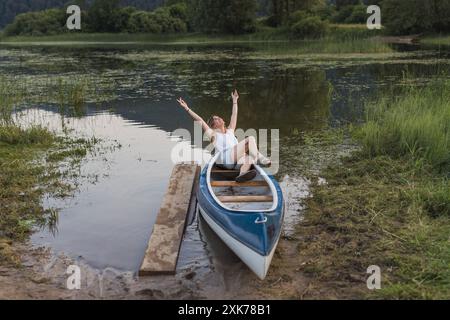 Portrait of a young woman relaxing in a canoe on a lake in nature Stock Photo