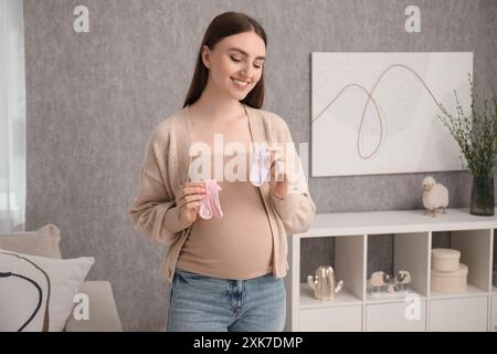 Expecting twins. Pregnant woman holding two pairs of socks at home Stock Photo