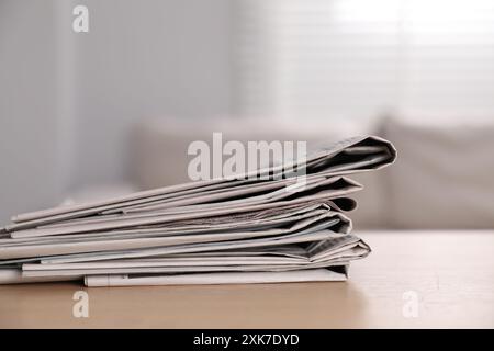 Stack of newspapers in different languages on table indoors Stock Photo