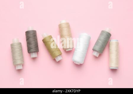 Flat lay composition with spools of sewing threads on pink background Stock Photo