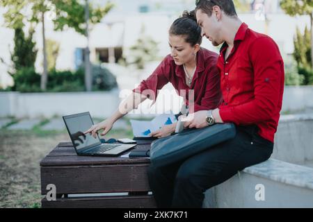 Business colleagues discussing project on laptop outdoors in the city Stock Photo