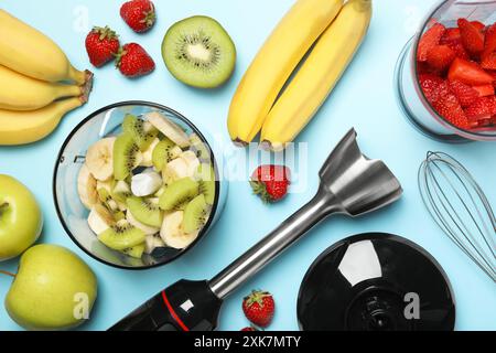 Hand blender kit, fresh fruits and strawberries on light blue background, flat lay Stock Photo