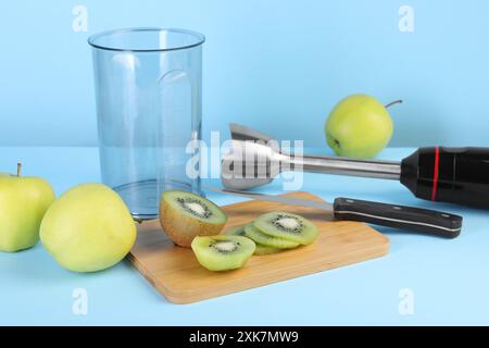 Hand blender kit, fresh fruits and knife on light blue background Stock Photo