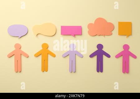Equality concept. Paper human figures and different speech bubbles on beige background, flat lay Stock Photo