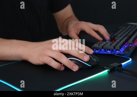 Gamer using modern wired computer mouse at black table, closeup Stock Photo