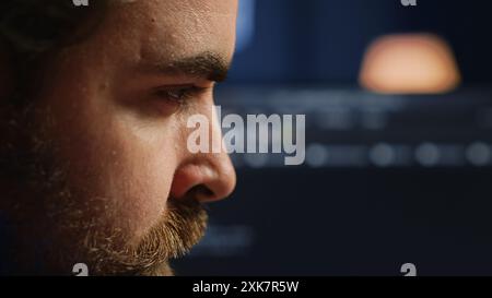 Developer in home office concentrating hard while doing coding on computer, extreme close up shot. Focus on IT admin paying close attention to screen while writing lines of code, camera A Stock Photo