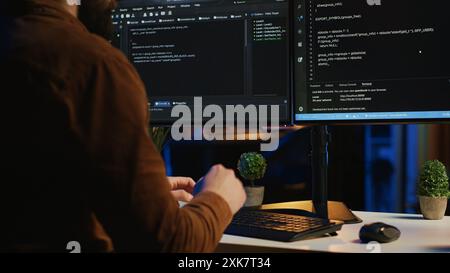Software engineer typing on keyboard buttons, writing lines of code in apartment office. Close up shot of IT expert pressing computer peripheral keys, working from home, programming Stock Photo