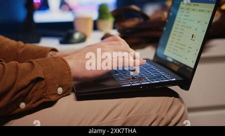 Freelancing computer scientist starting work in personal office at home, taking laptop out of bag. Self employed admin unpacking backpack, writing on notebook keyboard, camera A close up shot Stock Photo
