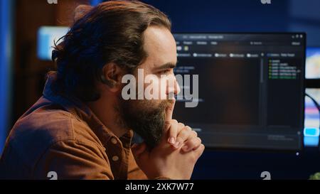 Cheerful software technician feeling satisfied after removing all bugs while coding on computer, close up. Smiling IT expert looking at screen, happy after solving script errors, camera A Stock Photo