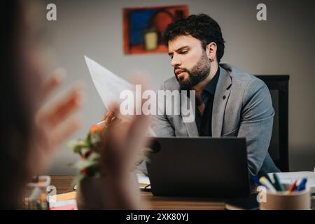 Focused male entrepreneur analyzing documents during multicultural team meeting Stock Photo