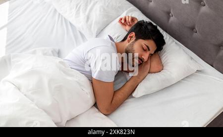 Asleep young arab man sleeping, resting peacefully in comfortable bed, lying with closed eyes, free space Stock Photo