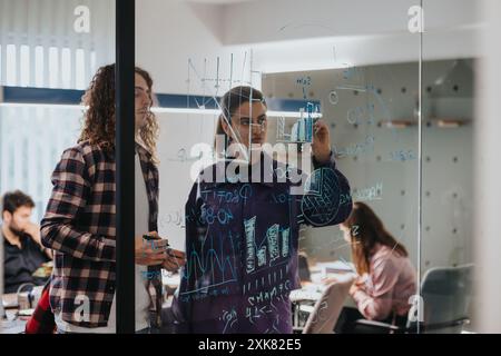 Business team collaboratively working on a financial analysis using a glass wall Stock Photo