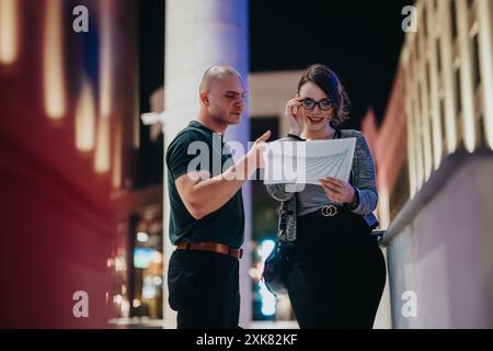 Colleagues discussing business reports at night in urban setting Stock Photo