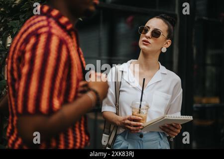 Businesspeople having an outdoor meeting while enjoying coffee and taking notes Stock Photo