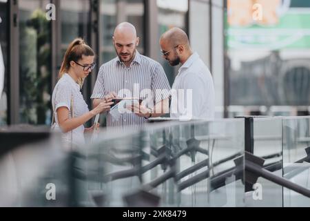 Professional business team collaborating outdoors on digital tablet Stock Photo