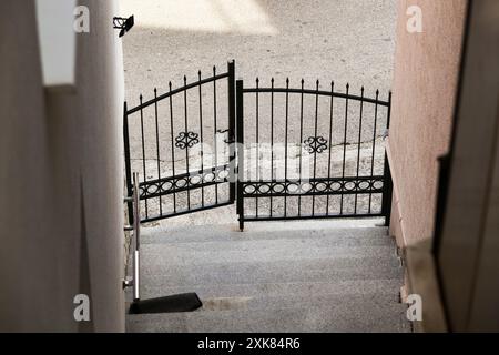 Grey steps in city and old metal gate. Detail of old staircase. Abstract wrought iron gate. Background Stock Photo