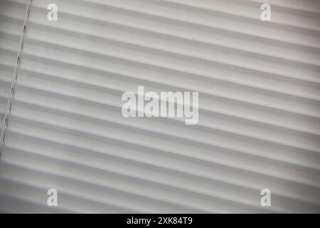 Pleated tightly closed blinds, closeup on window, white colour, white background. Modern blinds, sun protection. Stock Photo