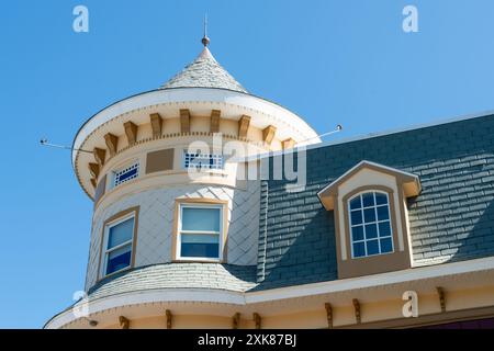 The top floor of a Victorian-style house with a large round turret and multiple windows. The exterior wall is yellow with white decorative trim. Stock Photo