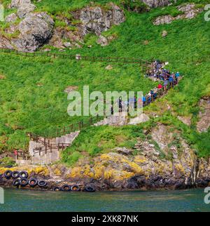 Visitors climb steps from the sea at North Haven on arrival at Skomer, an island off the Pembrokeshire coast of Wales, UK, famous for its wildlife Stock Photo