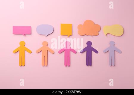 Equality concept. Paper human figures and different speech bubbles on pink background, flat lay Stock Photo
