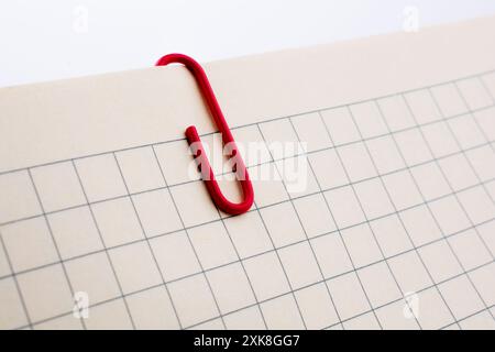 Colored paper clip on a checked notebook  page Stock Photo