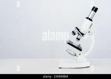 White microscope on table, microscope against white background. Light microscope Stock Photo