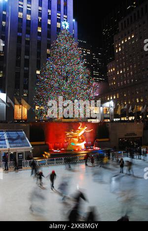 Ice skaters glide past the lighted Christmas tree in Rockefeller Center, New York City during the holiday season Stock Photo