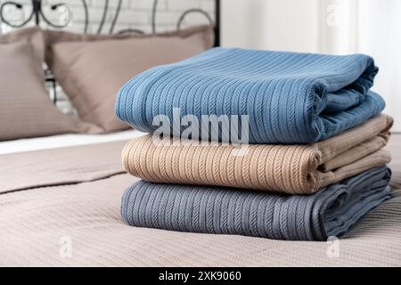 Stacked Blue and Beige Blankets on a Made Bed Stock Photo