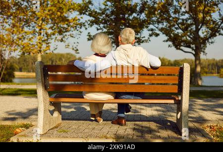 Senior Couple Embracing On Bench In City Park Stock Photo