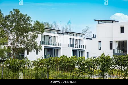 Brand new White apartment buildings in Phuket Thailand. Modern residential architecture with green trees and fence. Nobody, street photo. Stock Photo