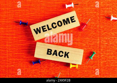 Life and business motivational inspirational concept. Welcome Back, text words on wooden blocks with a hand on an orange background Stock Photo