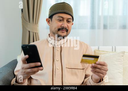 Cheerful arab man with credit card and smart phone shopping online., online shopping on smart phone. E-commerce, internet banking concept. Stock Photo