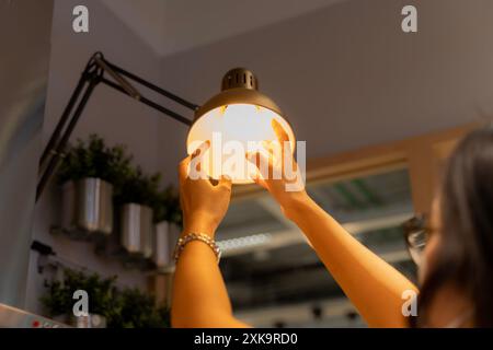 Hand woman changing with new LED lamp light bulb,Power saving concept. Reusing and recycling existing materials for future growth of business and envi Stock Photo