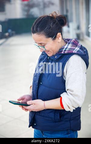 woman looking in mobile phone in the hands is smiling Stock Photo